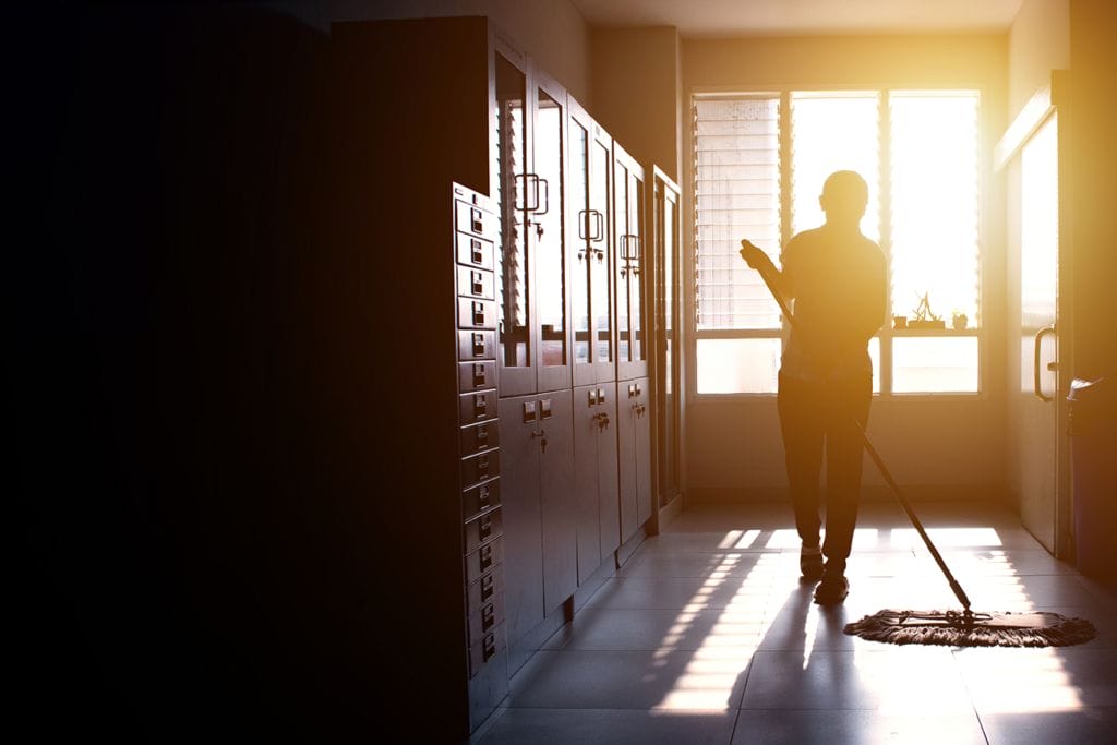 Janitor woman mopping floor in hallway office building or walkway after school or classroom with copy space.